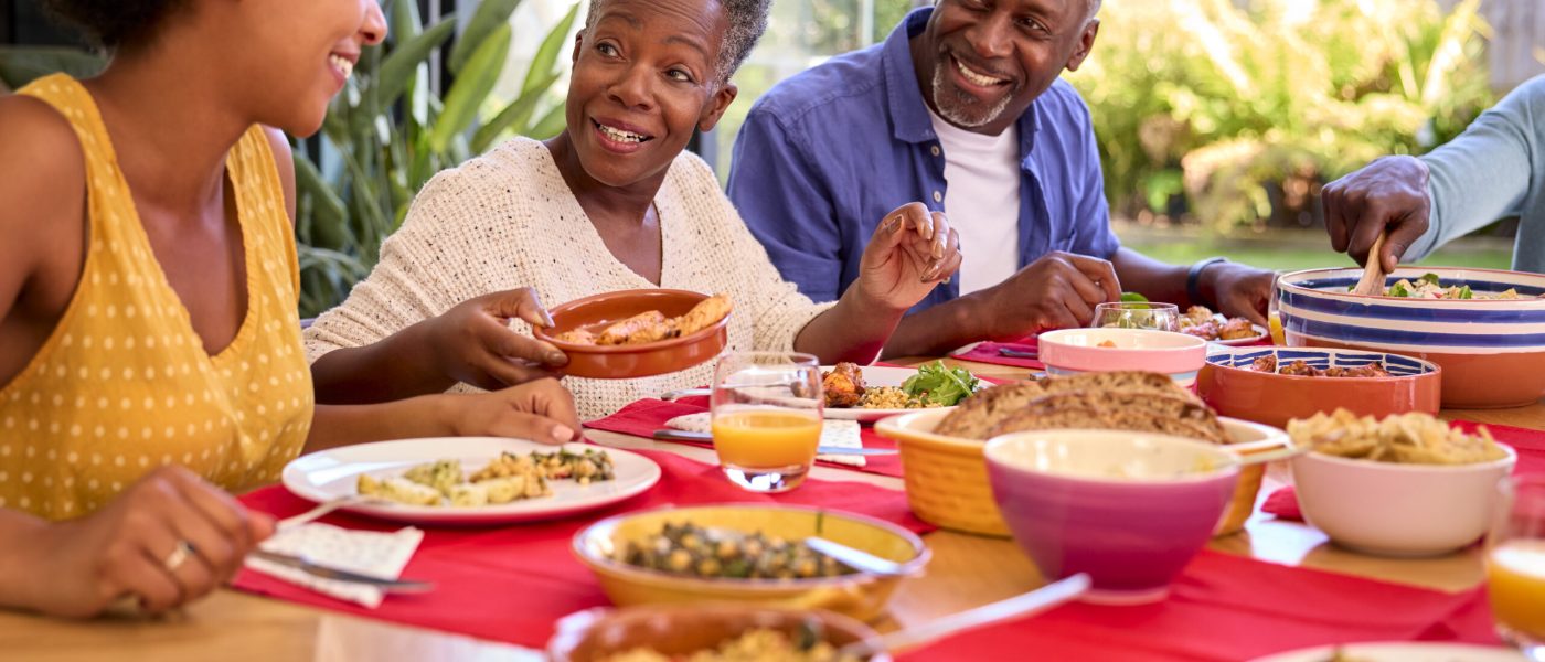 Parents With Adult Offspring Sitting Around Table At Home Enjoying Meal Together