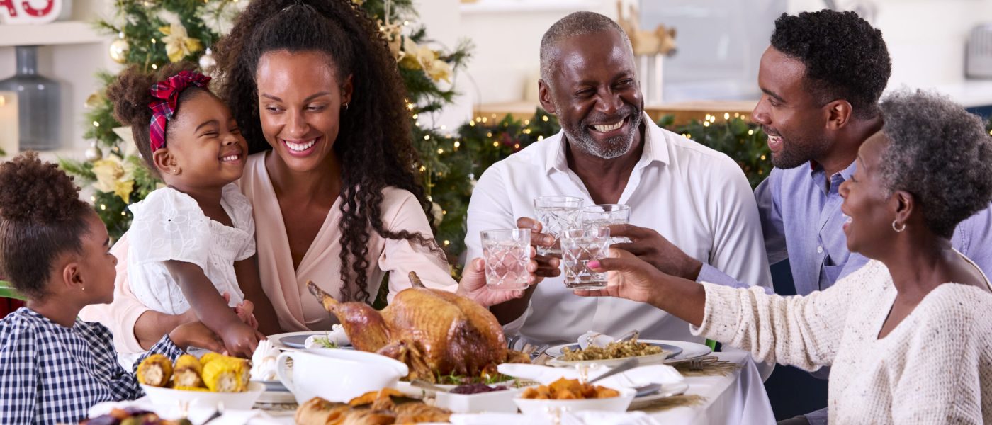 Multi-Generation Family Celebrating Christmas At Home Eating Meal And Making Toast With Water